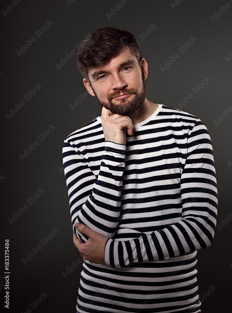 Obraz premium Bearded happy emotional man thininking about with fun grimacing face on grey background. Closeup portrait
