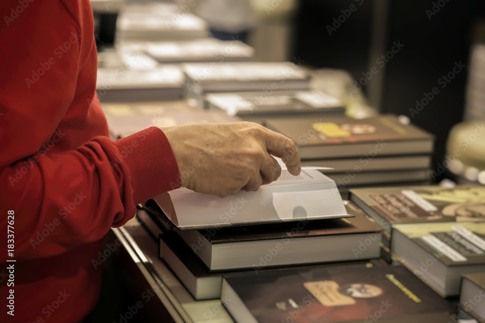 Close-up of hands of elderly person with open book, bookstore, library. Real scene. Education concept, Self-study, reading fiction, pension, interests in elderly, life style Close-up of hands of elderly person with open book, bookstore, library. Real scene. Education concept, Self-study, reading fiction, pension, interests in elderly, life style