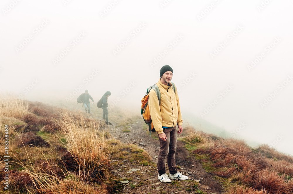 mountain landscape in the autumn fog. man, boy traveler standing on a mountain in a yellow jacket