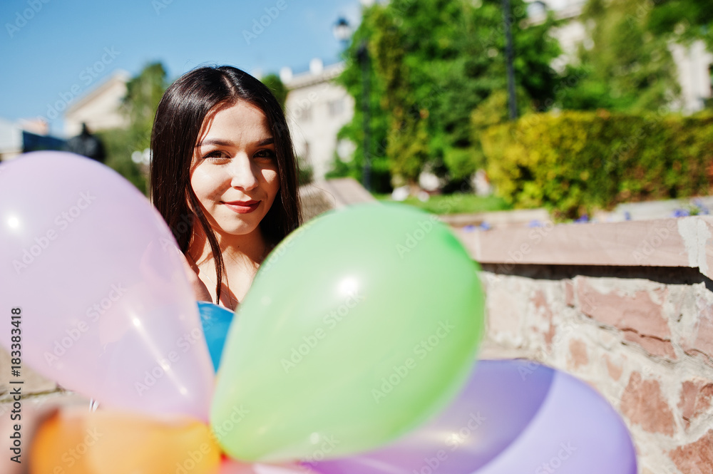 Naklejka premium Gorgeous brunette girl at street of city with balloons at hands.