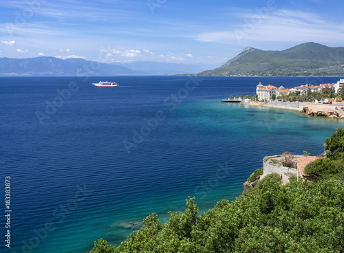 View of the azure sea and the Greek spa resort with a sailing ferry photo