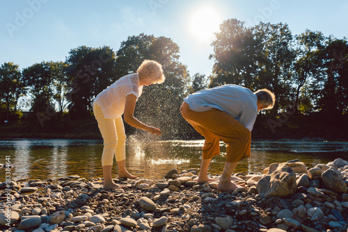 Senioren Frau und Mann fitschen Steine am Fluss im Wasser photo
