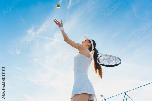 Frau spielt Tennis und gibt den Aufschlag, sie wirft den Ball in die Luft © Kzenon