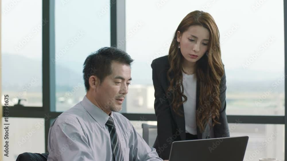 asian businessman and businesswoman working together in office using laptop computer