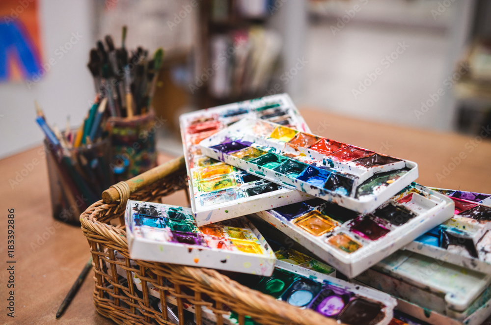 Set of watercolor paints in basket. Creative studio Set of watercolor paints in basket. Creative studio