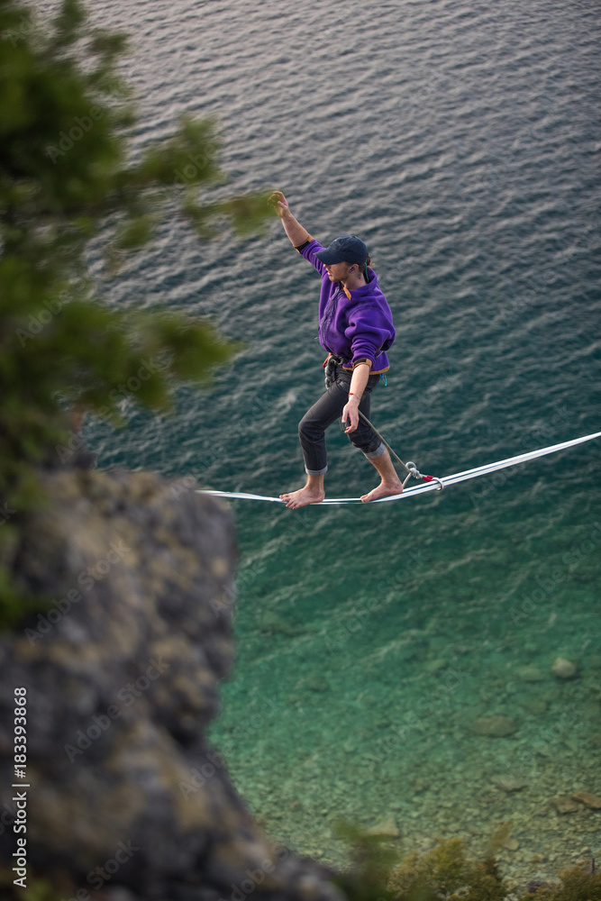 Fototapeta premium Man walking a high line slack line high above water