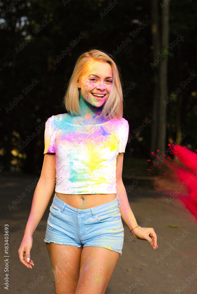 Positive blonde woman in white t shirt and jeans shorts covered with  colorful Holi powder Stock-Foto | Adobe Stock