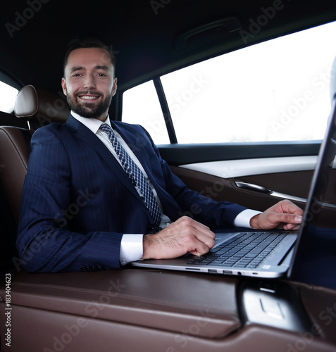 successful man working with laptop sitting in car