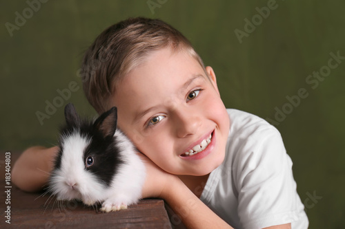 Cute boy with funny rabbit on color background