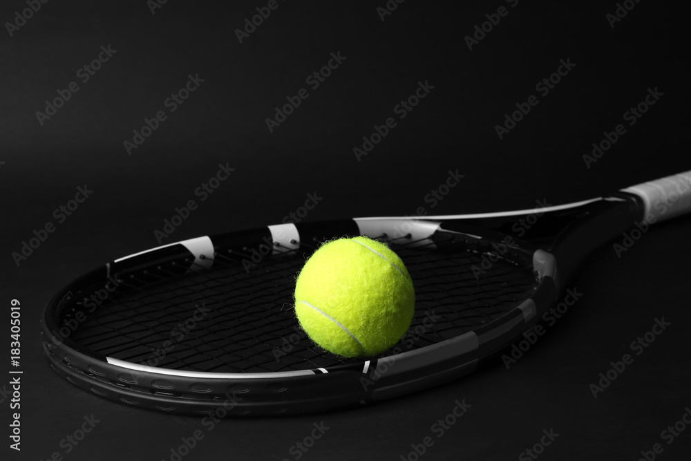 Tennis racket and ball on dark background
