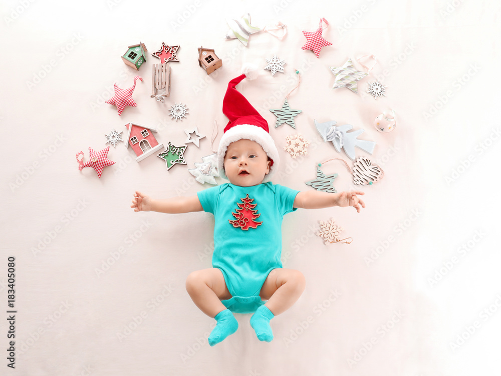 Cute baby in Santa hat and Christmas decorations on light background Cute baby in Santa hat and Christmas decorations on light background