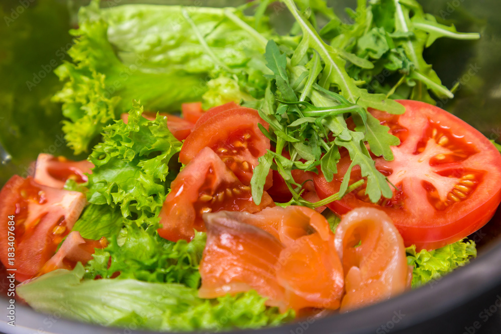 preparation of salad with red fish, tomato and greens