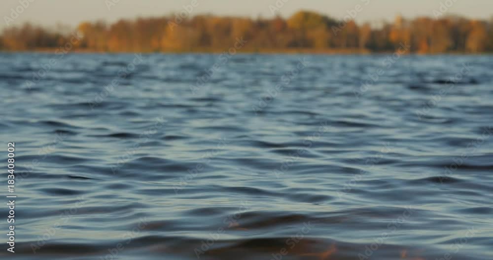 View of the lake and waves from the low shore.Calm water background. Telephoto lens shot with shallow depth of field. Low angle view View of the lake and waves from the low shore.Calm water background. Telephoto lens shot with shallow depth of field. Low angle view