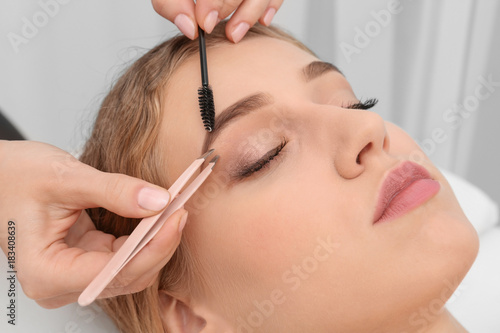 Young woman having eyebrow correction procedure in beauty salon photo