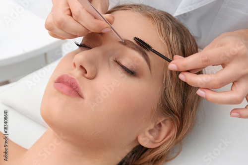 Young woman having eyebrow correction procedure in beauty salon