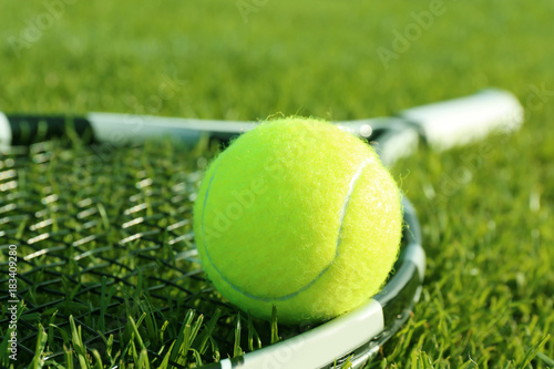 Tennis racket and ball on green grass
