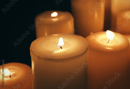 Many burning candles on dark background, closeup