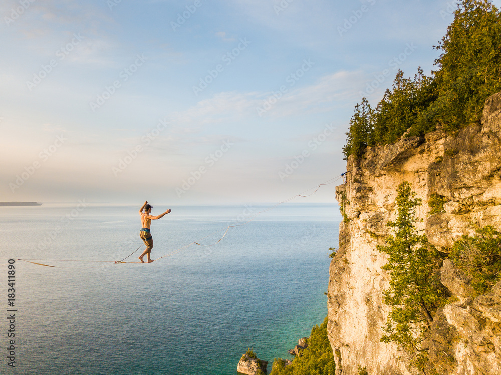 Man walking a high line slack line high above water