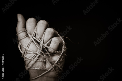 Fotografía a woman hand tied with wire on dark background in low key