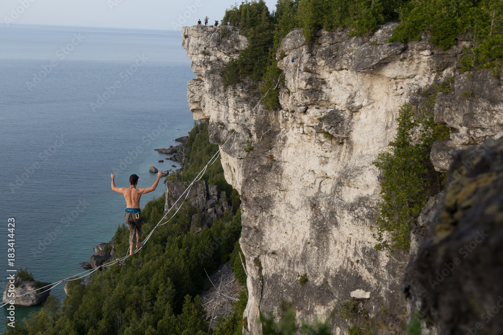 Man walking a high line slack line high above water