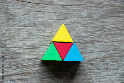 Mulit color toy block compound as triangle shape on wood background photo