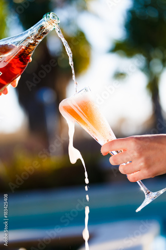 Waiter is pourring sparkling wine into a woman glass at the outdoor party.  Celebration concept