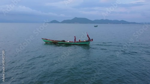 The mountains of Kep Cambodia in the background, a fisherman stands and look towards Vietnam as he powers through the Gulf of Siam in this aerial view. photo