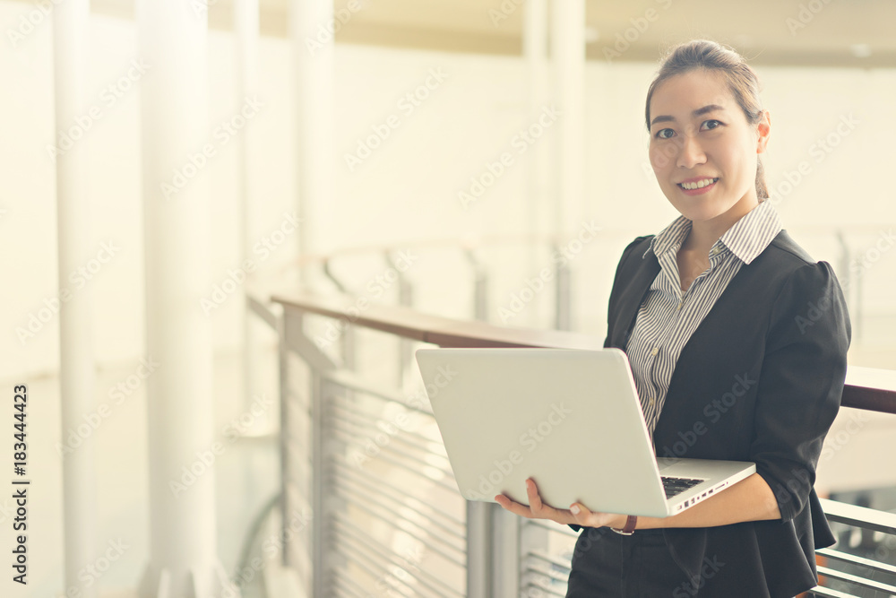 Beautiful asia business woman smiling and holding laptop in the office Beautiful asia business woman smiling and holding laptop in the office