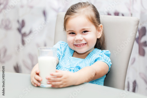 Little child girl drinking a milk at kitchen