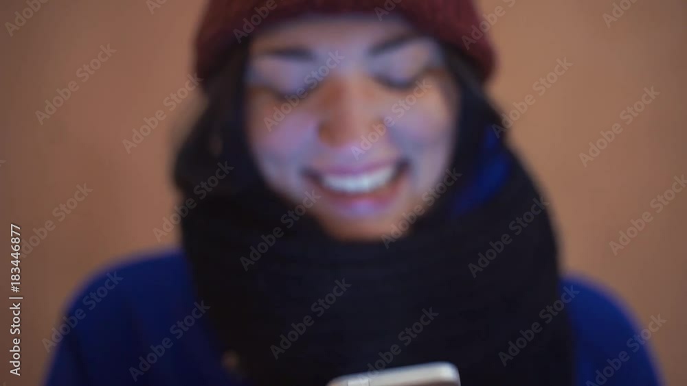 Close up of young woman smiling using smartphone standing outdoors Close up of young woman smiling using smartphone standing outdoors