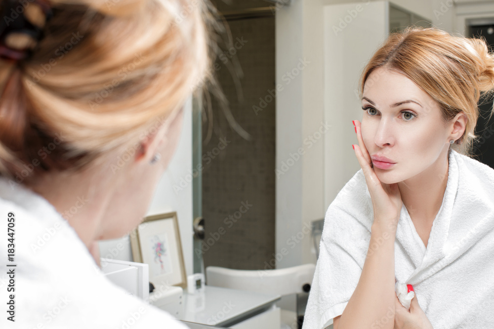 Fototapeta premium woman looks at herself in the bathroom mirror