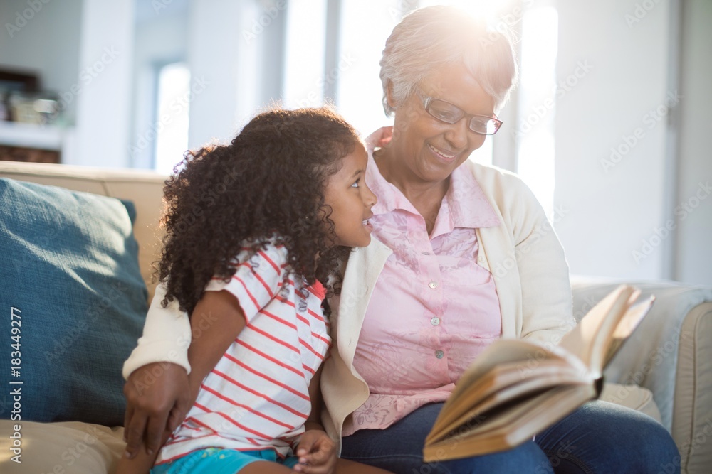 Grandmother and daughter reading book in living room Grandmother and daughter reading book in living room
