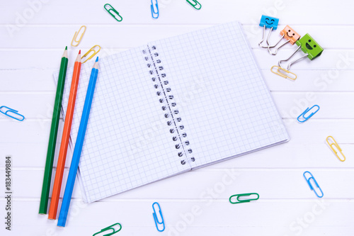 open notebook with blank pages and pen and pensil on white wooden desk