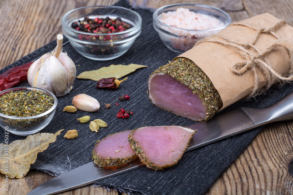 Smoked ham on wooden table with aromatic herbs and spices, natural product