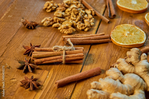 Fototapeta Naklejka Na Ścianę i Meble -  Sticks of cinnamon and anise stars on wooden brown background. Ingredients for mulled wine: dried fruits, orange, ginger, cinnamon, anise and nuts. Close up view