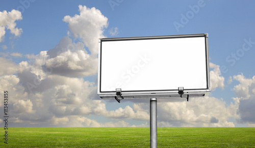 Empty billboard in a field with a blue sky