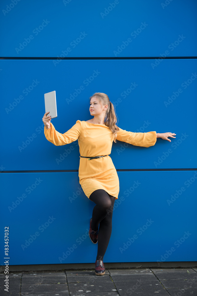 Young woman taking selfie on blue background