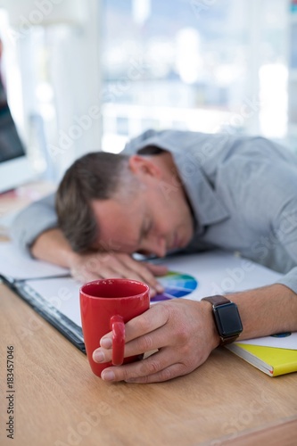 Tired male executive sleeping on desk photo