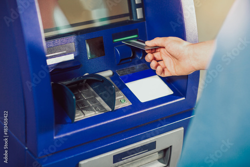 Man uses an ATM card inserted into the ATM machine for cash.