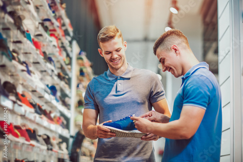 Two man deciding on new sports shoes in sports store photo