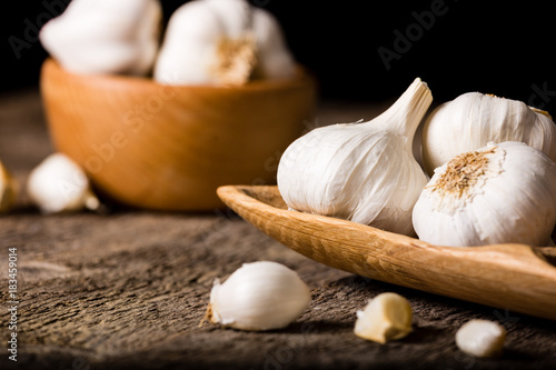 Garlic, Garlic cloves and Garlic bulb in vintage handmade wooden bowl. Front view.