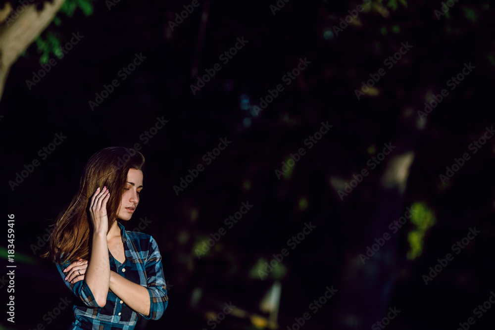 Fashion outdoor portrait of gorgeous brunette woman in checkered blue dress - spring style. Fashionable young girl in trendy clothes posing at city park. Copy space Fashion outdoor portrait of gorgeous brunette woman in checkered blue dress - spring style. Fashionable young girl in trendy clothes posing at city park. Copy space
