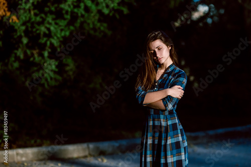 Fashion outdoor photo of beautiful young woman in elegant blue dress. Portrait of gorgeous long hair woman in checkered dress posing outdoors. Copy space