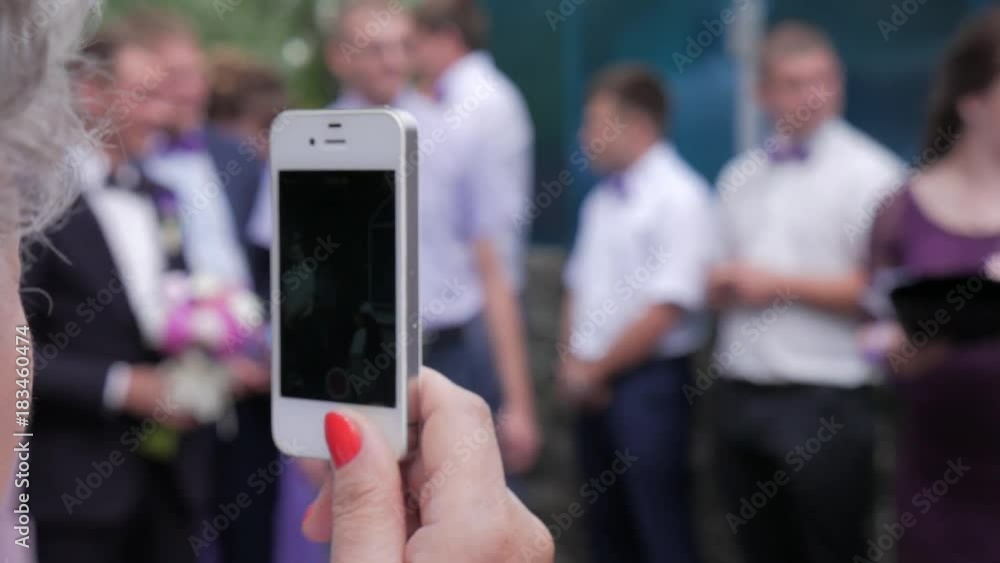 Female hand with phone shoots video of the people at the party. Female hand with phone shoots video of the people at the party.
