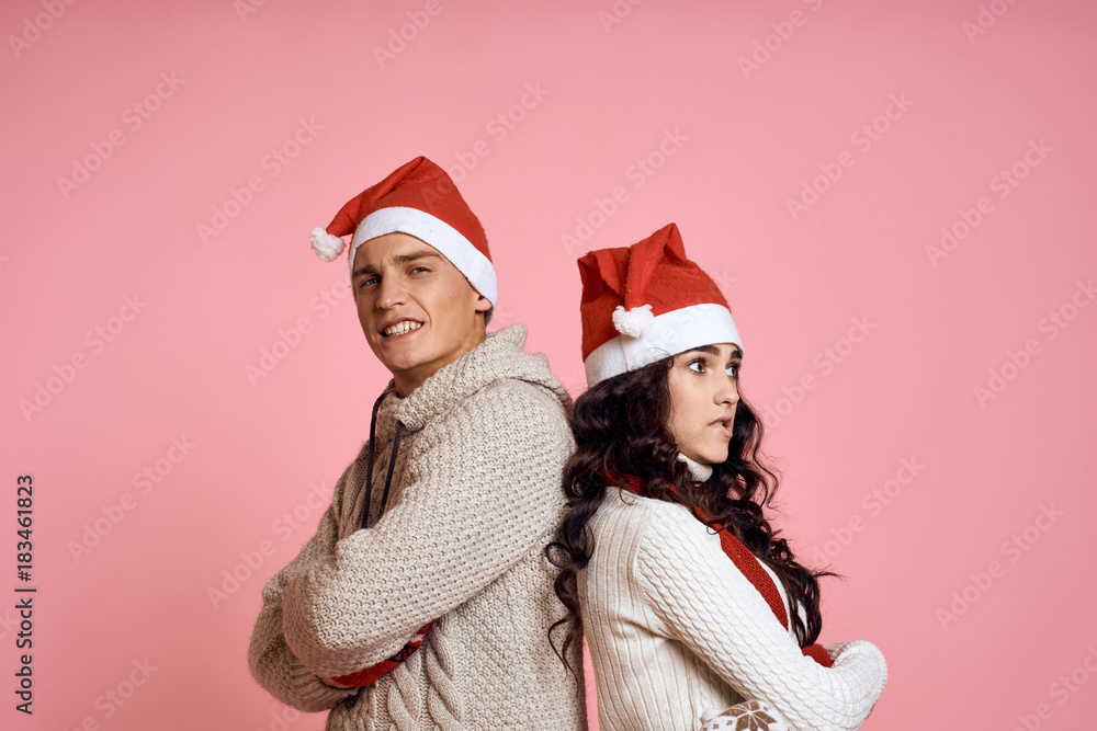 man and woman are standing with their backs to each other in New Year's hats, emotions, holiday, new year, christmas, couple, light pink background man and woman are standing with their backs to each other in New Year's hats, emotions, holiday, new year, christmas, couple, light pink background