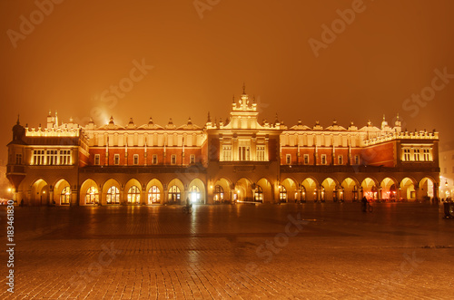 Market hall at main Cracow square at misty night with golden sky