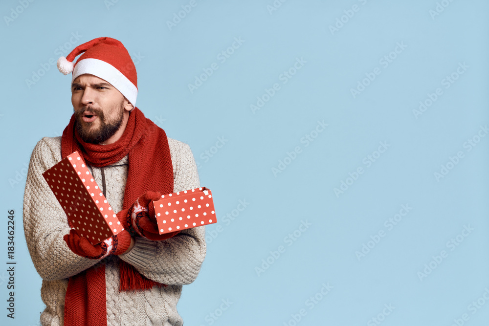 2083816 a man with a beard in a New Year hat holds in his hands an open box, a gift, a new year, a Christmas, a holiday, a light background, a free copy space 2083816 a man with a beard in a New Year hat holds in his hands an open box, a gift, a new year, a Christmas, a holiday, a light background, a free copy space