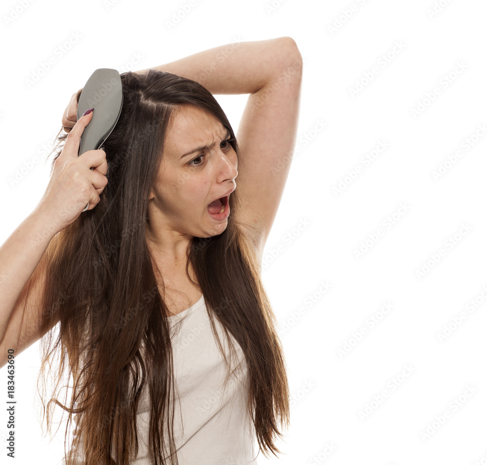 young beautiful woman has a problem with the combing her long hair young beautiful woman has a problem with the combing her long hair