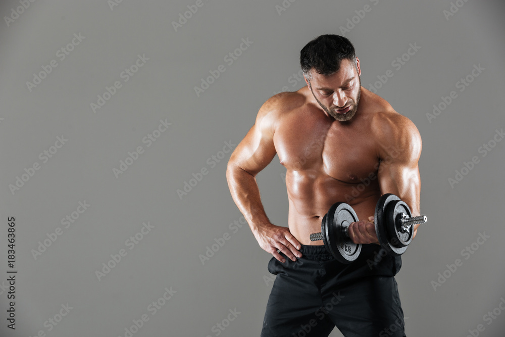 Portrait of a serious strong shirtless male bodybuilder lifting