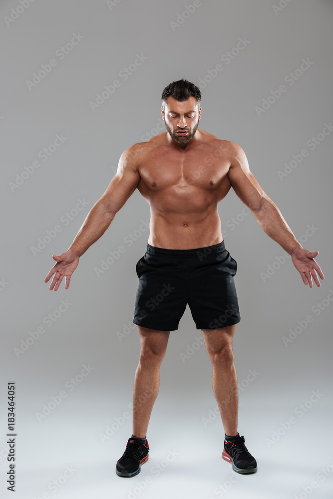 Obraz premium Full length portrait of a confident strong shirtless male bodybuilder